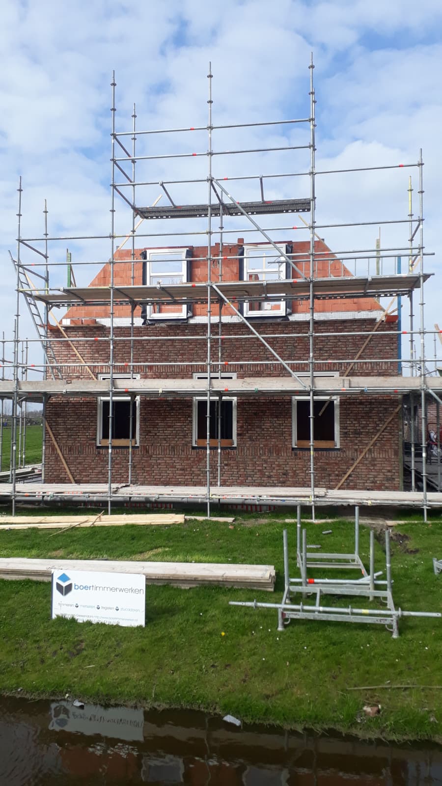 Nieuwbouw woning in aanbouw met steigers en bakstenen gevel