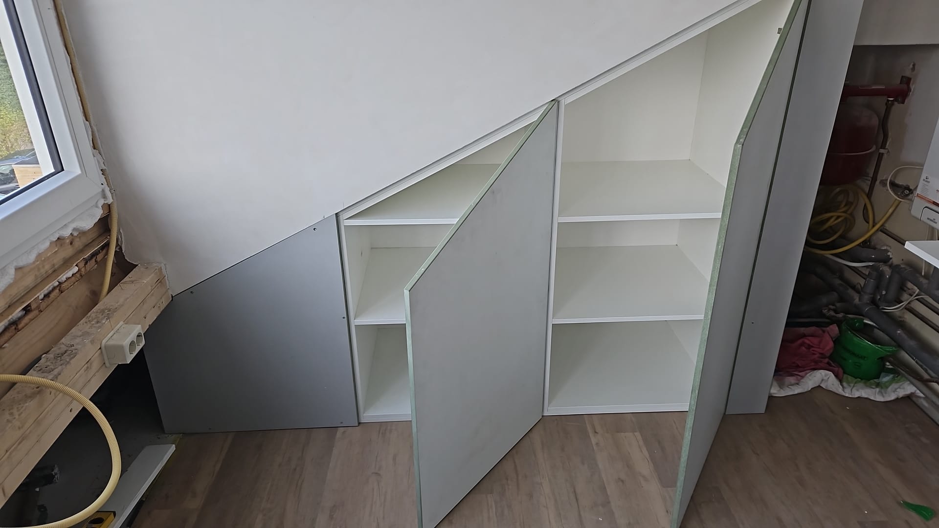 Inbouwkast op maat met geopende deuren en witte legplanken onder een schuine wand (foto 1 van 2)